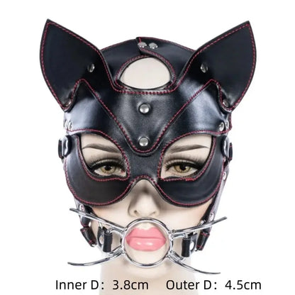 Máscara BDSM con ball gag metálico de 3.8 cm interno y 4.5 cm externo. Diseño de cuero sintético con orejas de gato y costuras rojas.